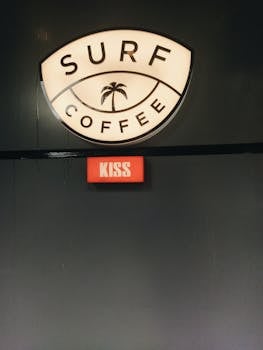 Vintage style café sign reading Surf Coffee with a red Kiss button, perfect for trendy coffee lovers.