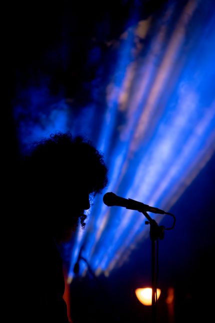 Singer silhouetted against blue stage beams — photo by Athanasios Zoidis on Pexels