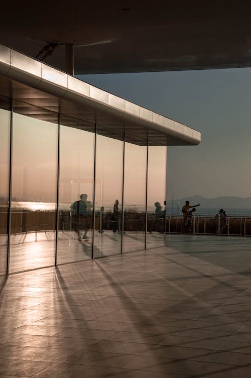 Reflection of People and Sunset in a Modern Glass Building Facade 