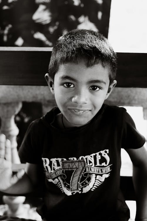 A Grayscale Photo of a Young Boy in Black Shirt Smiling