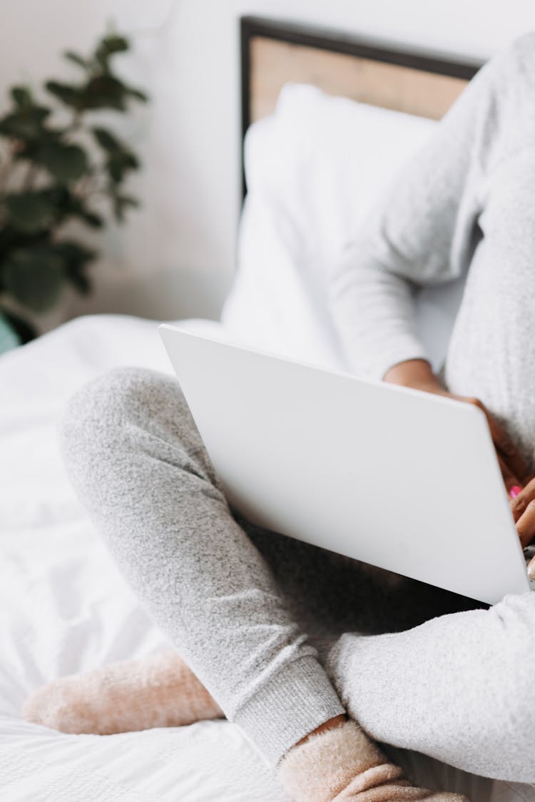 Woman Sitting On Bed With Laptop