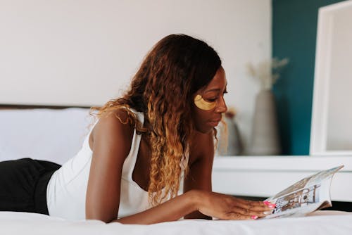 Free Woman reading magazine lying in bed Stock Photo