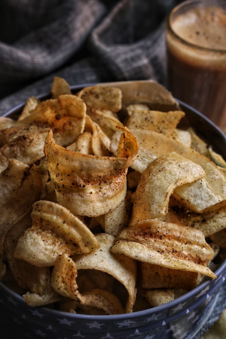 Spicy Chips In Blue Bowl Standing Next To Glass Of Coffee