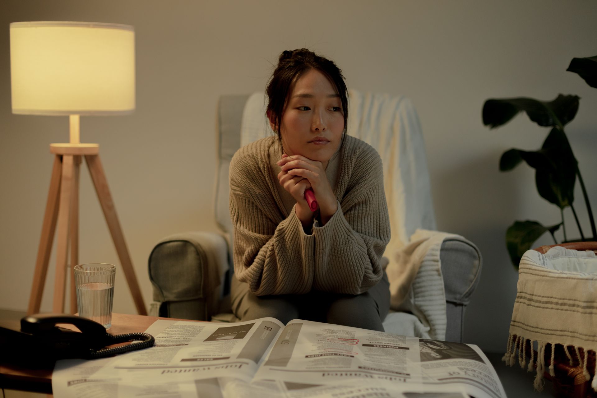 A woman in an armchair, contemplating job search in a cozy living room.