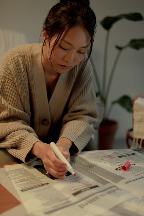 Free A woman highlighting job listings in a newspaper at home, focused on her work. Stock Photo