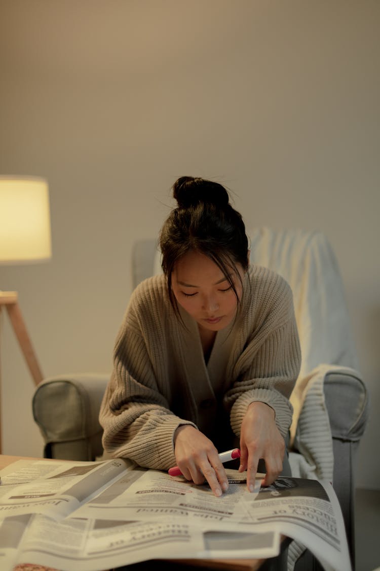 Woman Looking Through Newspaper During Job Search