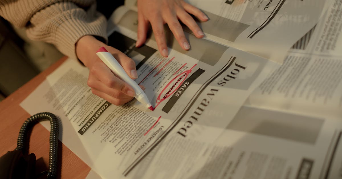 An adult woman highlights job ads in a newspaper, focusing on employment opportunities.