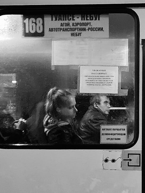 Interior view of a Russian bus with two seated passengers. Monochrome.