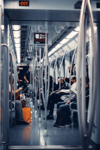 Passengers in a subway train practicing safety measures with face masks, reflecting urban commute during pandemic.