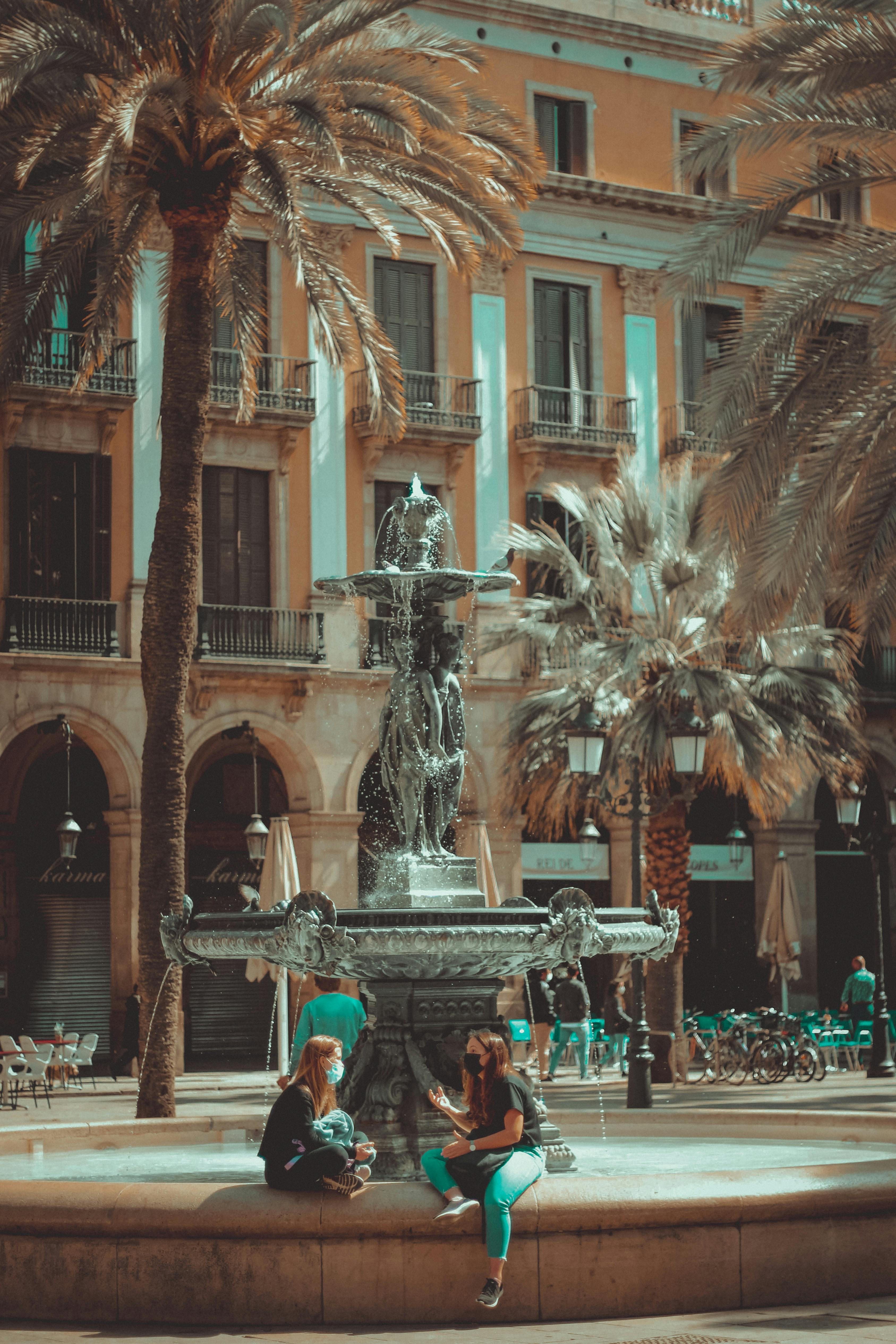 women sitting near the water fountain while having conversation