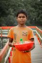 Teenage boy holding bowl with bottled drink and foiled snacks