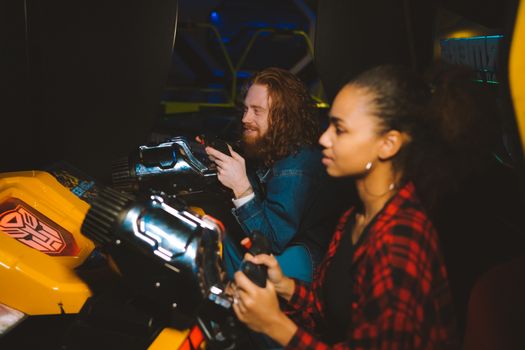 A couple immersed in playing arcade games together, showcasing fun and leisure in a vibrant setting.