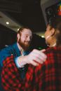 A Bearded Man in Denim Jacket Tapping a Woman's Shoulder in Plaid Long Sleeves