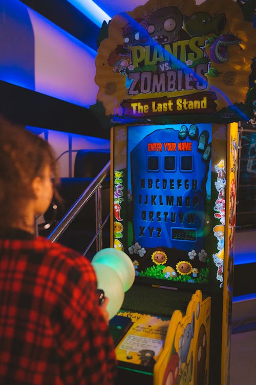 A Person in Plaid Long Sleeves Playing on Arcade Machine