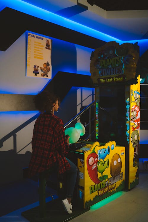A Woman in a Plaid Shirt Playing in an Arcade