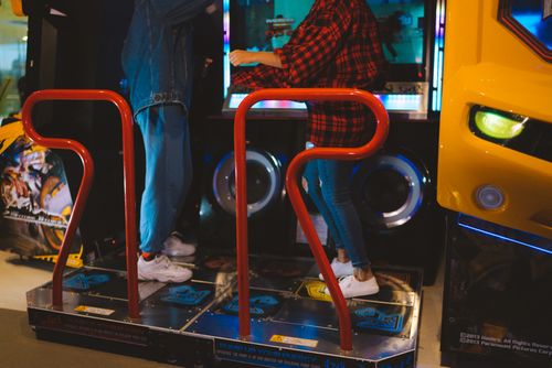 Free Adults having fun on a dance arcade game indoors. Vibrant, recreational, gaming fun. Stock Photo