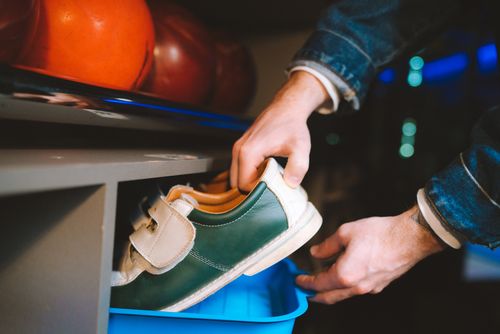 Free Close-up of hands handling bowling shoes with bowling balls in the background. Stock Photo