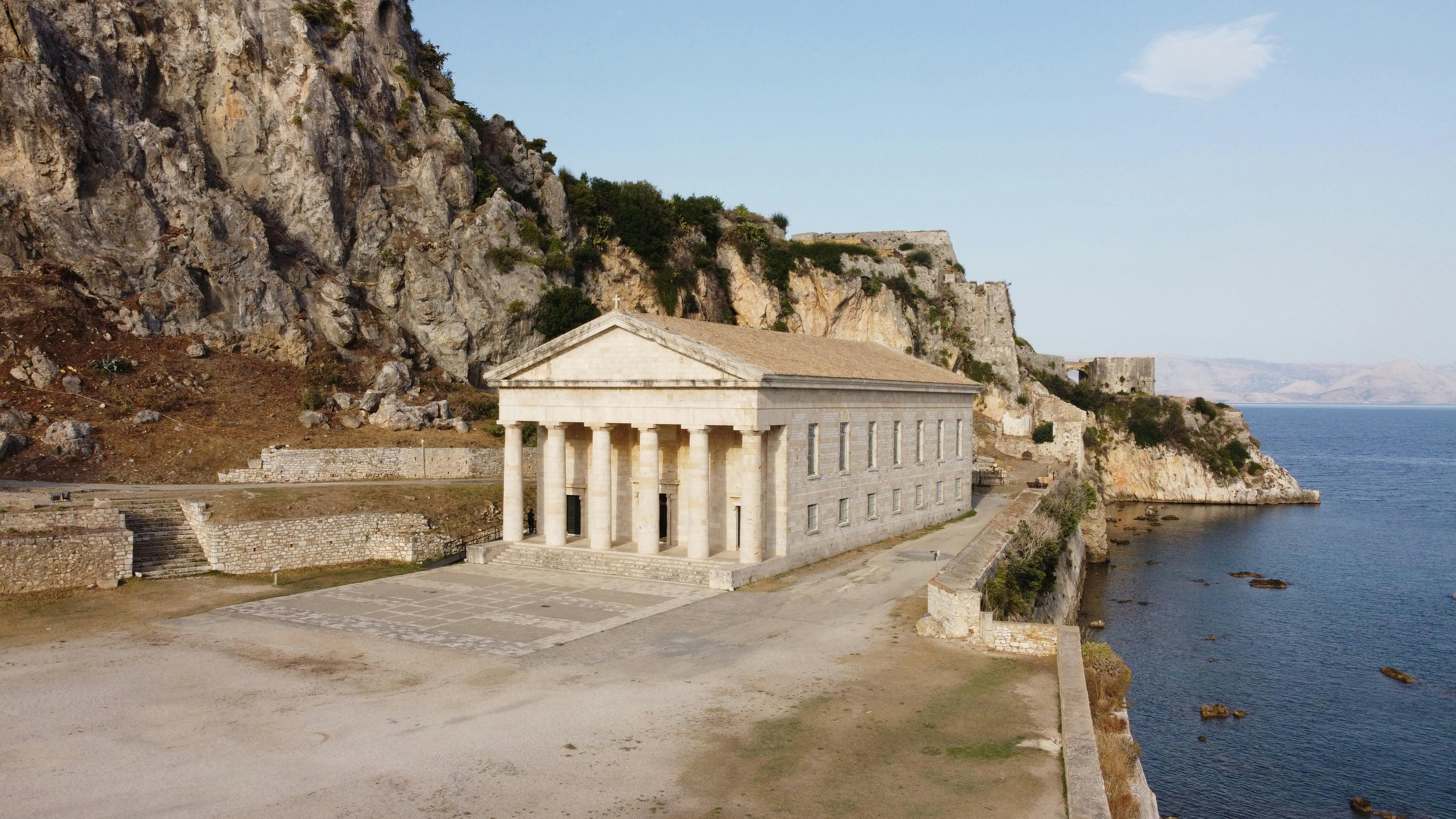 white concrete building near mountain and body of water