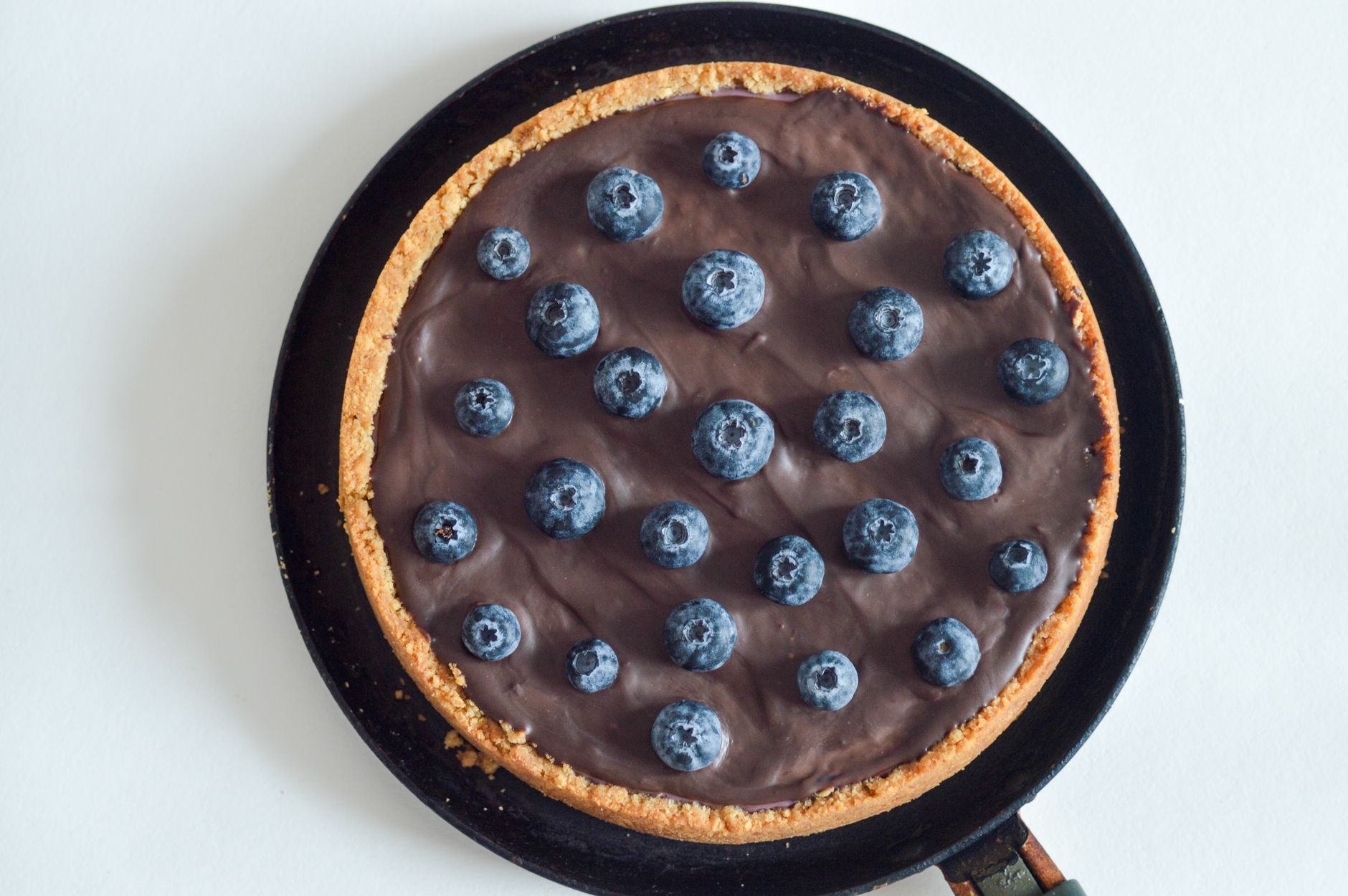 Moist slice of keto blueberry cake with fresh berries on top on a wooden plate