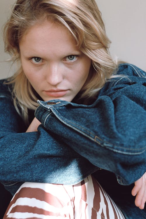 Teenage blond woman sitting with hands folded under her chin