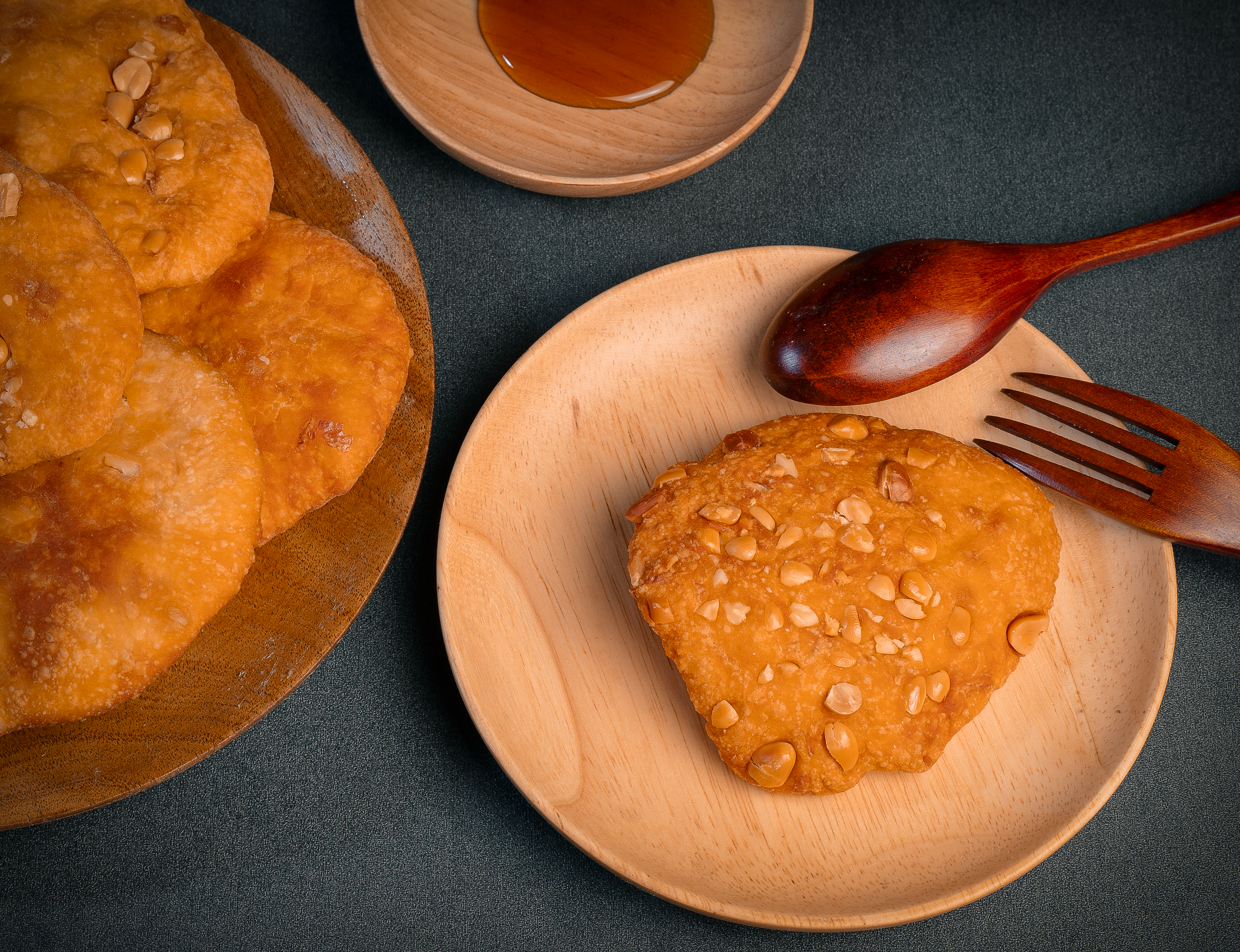 High angle shot of golden biscuits with nuts, served on wooden plates with honey.