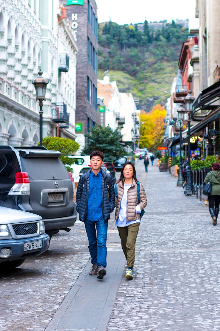 Asian Couple Walking Along Atmospheric City Street In Autumn