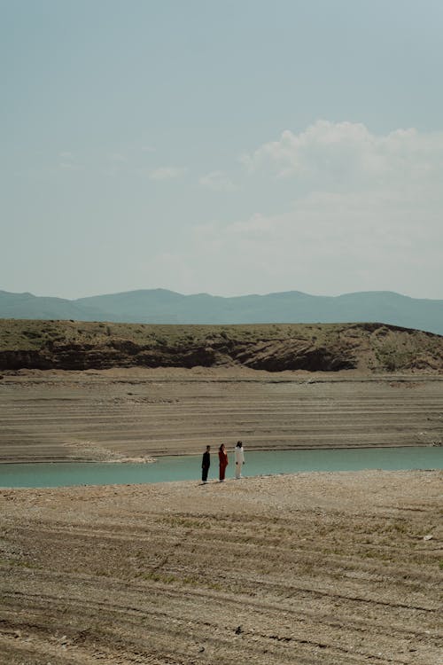 People Standing near a Body of Water in Distance 