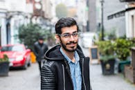 Friendly young man in glasses and casual clothes in street