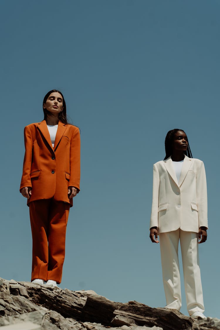 A Low Angle Shot Of Women Wearing Blazers And Pants Standing On The Rock