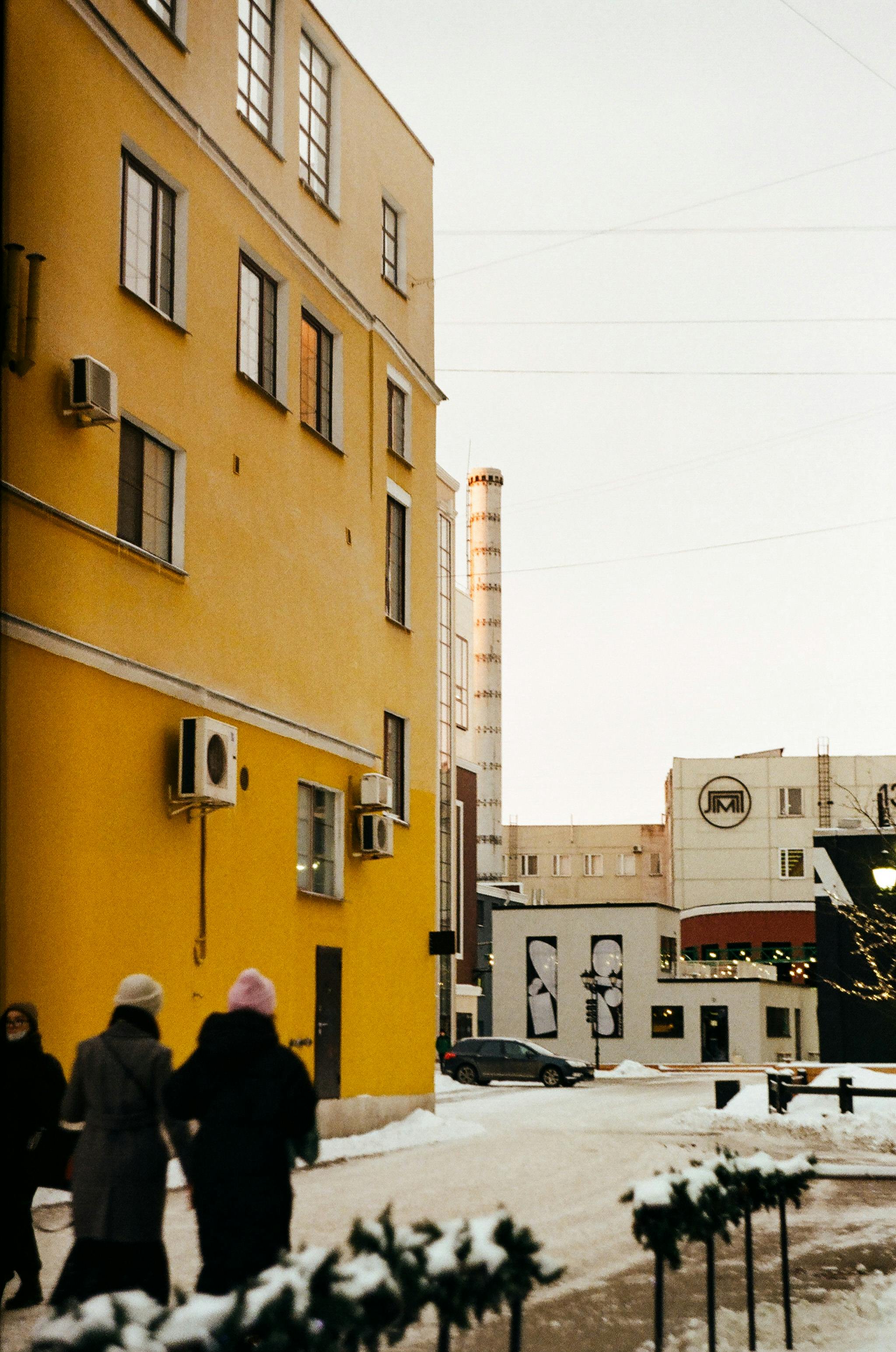 Vibrant city street scene in winter with pedestrians and a yellow building.