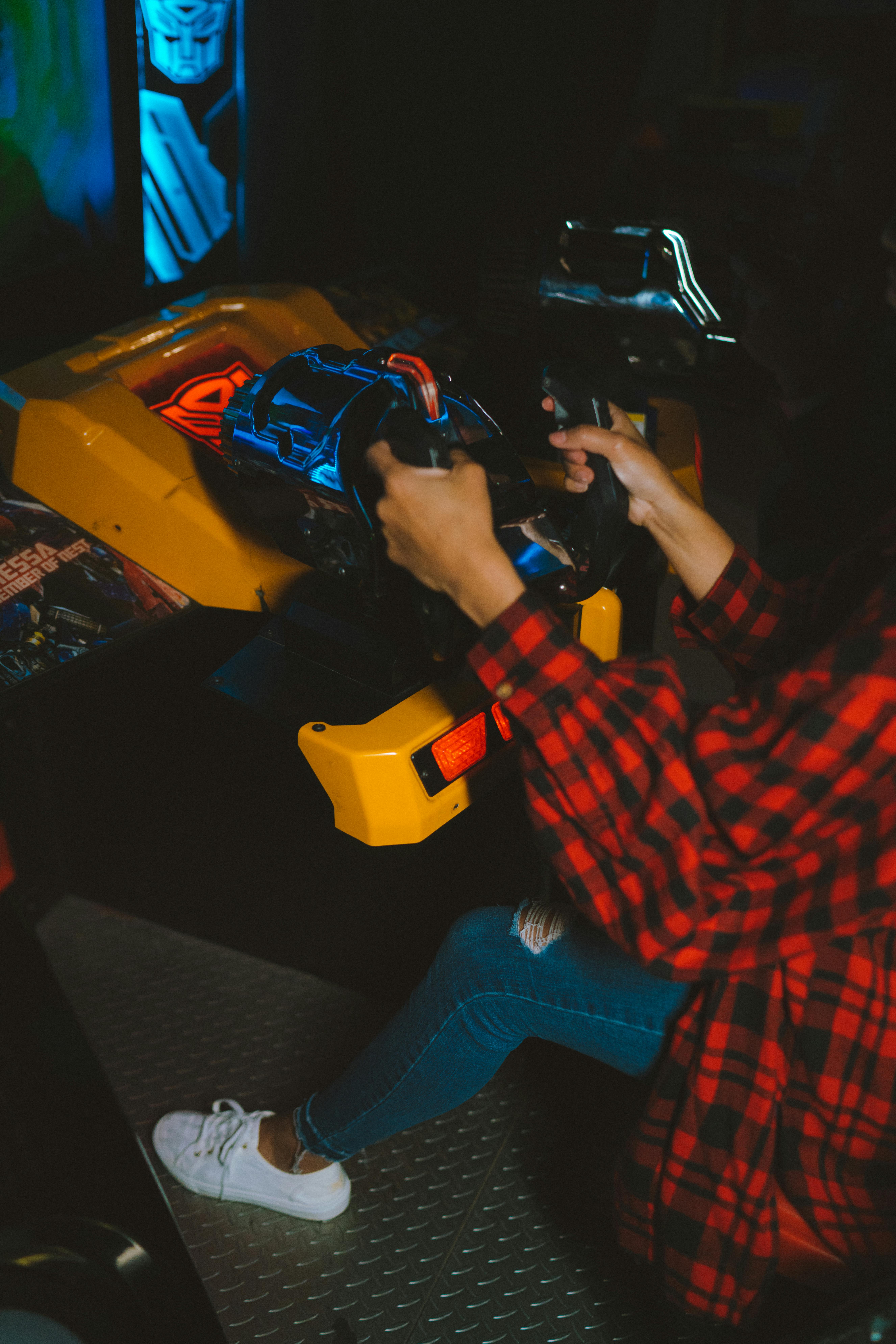 person in red and black checkered dress shirt and blue denim jeans sitting on yellow plastic