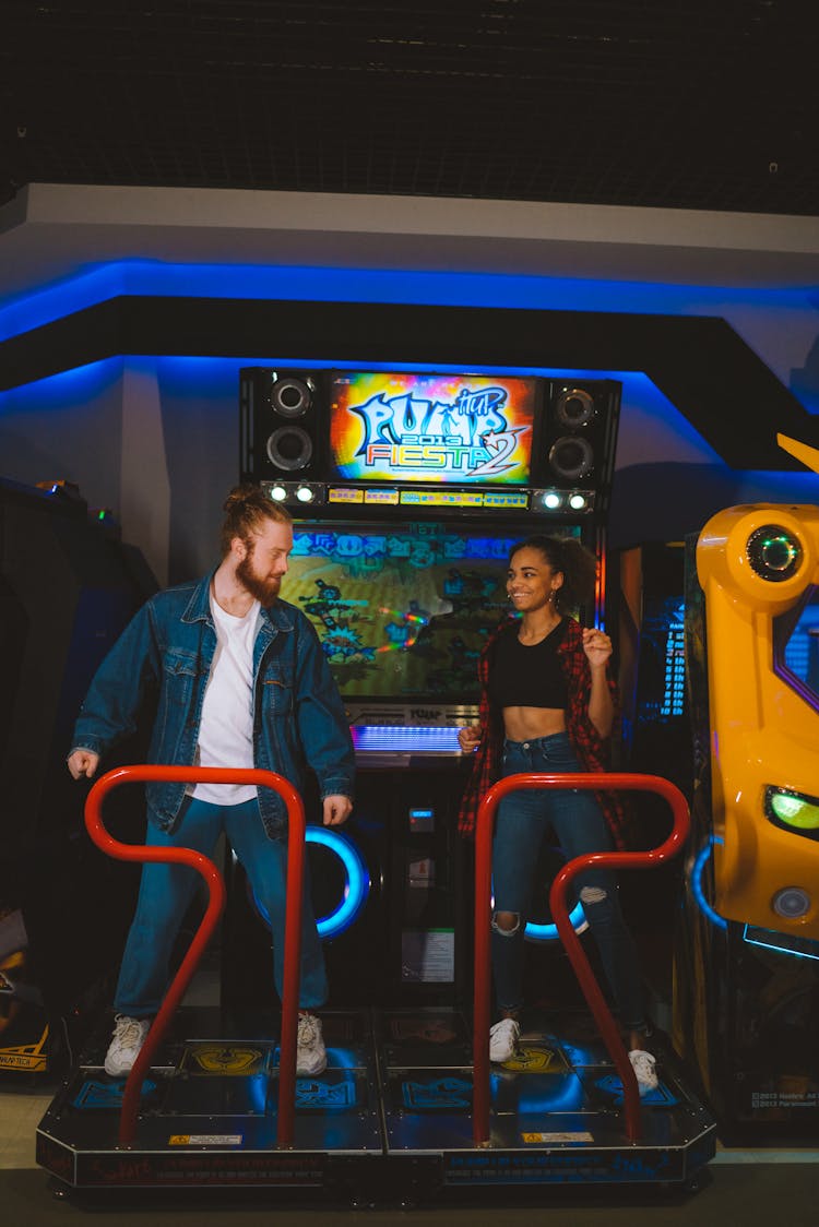 A Couple Standing On An Arcade Game