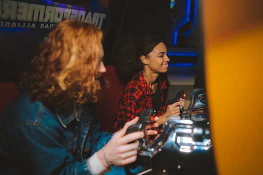 Smiling interracial couple having fun playing arcade games together indoors.