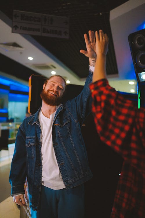 A Man in Denim Jacket Smiling while Doing High Five