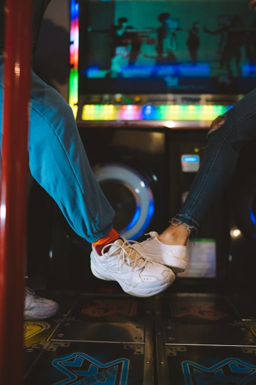 Close-up of People Playing a Dance Game in an Arcade 