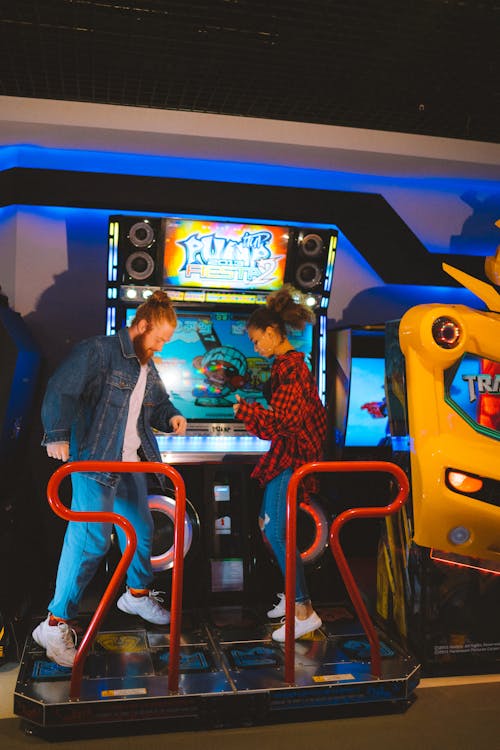 A Man and Woman Stepping on the Arcade Machine