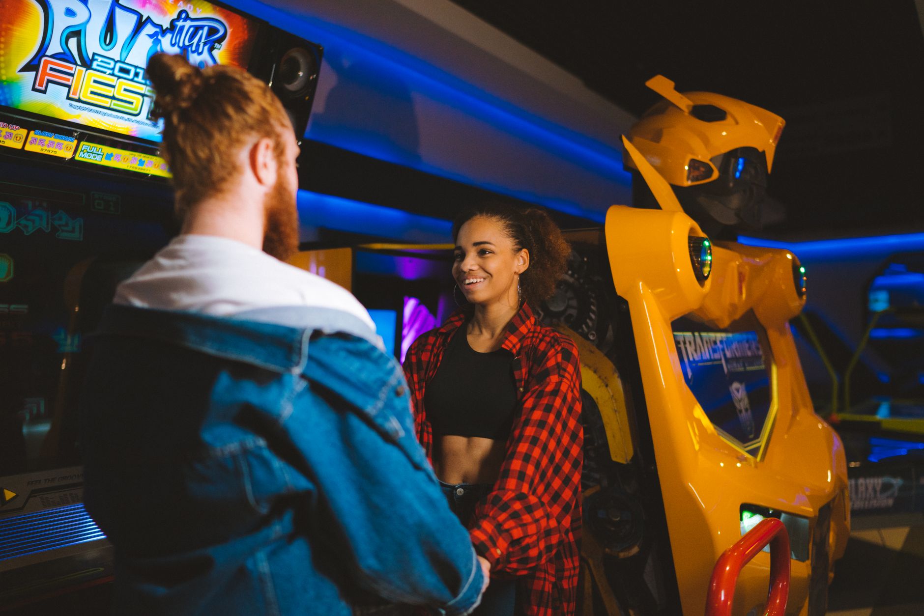arcade games rental cairo — Happy couple holding hands and smiling in a vibrant arcade setting.