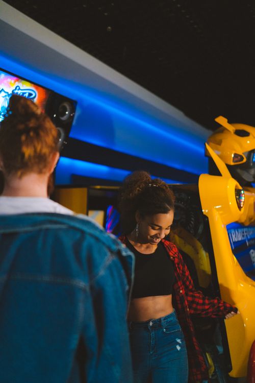 Free Two young adults enjoying arcade games indoors, capturing a moment of leisure and fun. Stock Photo