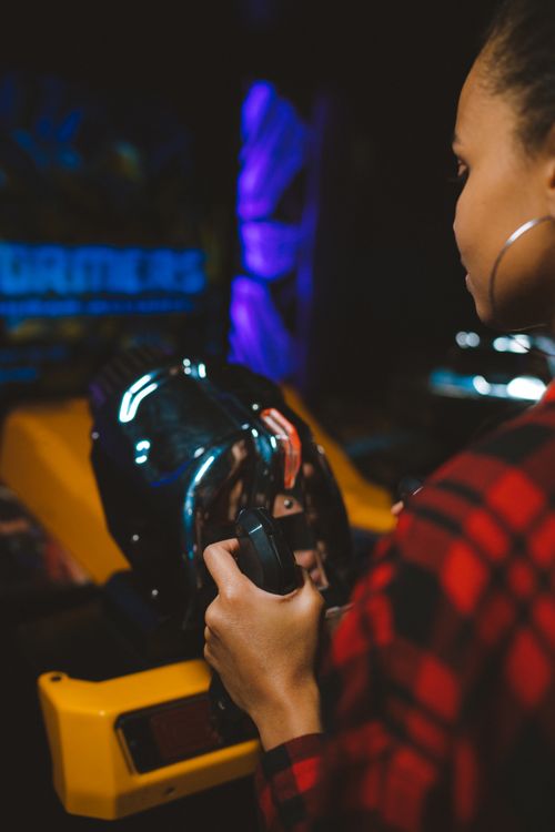 Free A young woman plays an immersive arcade game, focusing intently on the screen. Stock Photo