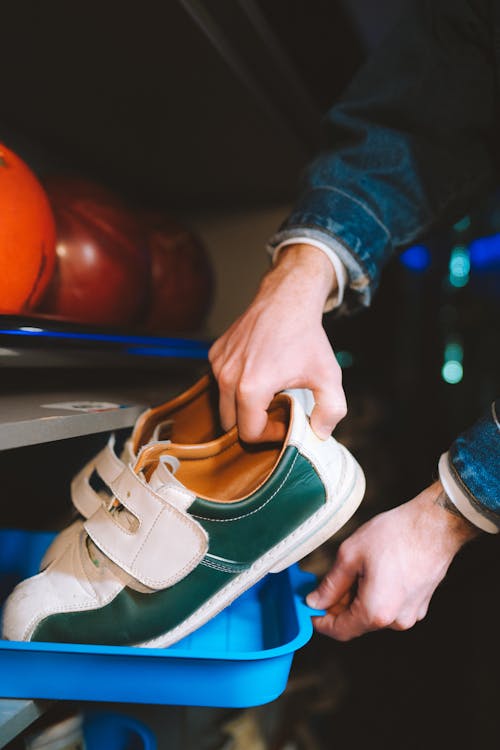 Person in Blue Denim Jacket Holding Bowling Shoes