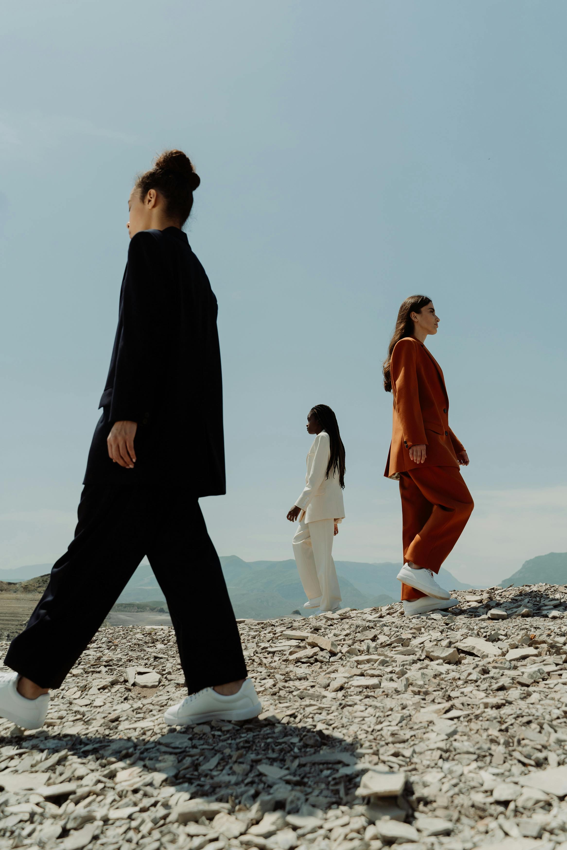 women wearing suits in different colors walking in a desert