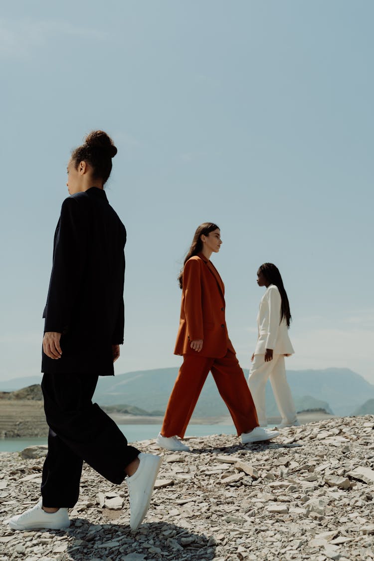 A Low Angle Shot Of Women Walking On A Rocky Shore