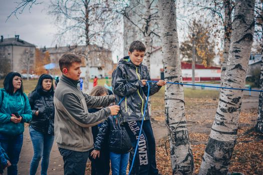 Kids enjoying an outdoor rope activity among birch trees during fall.