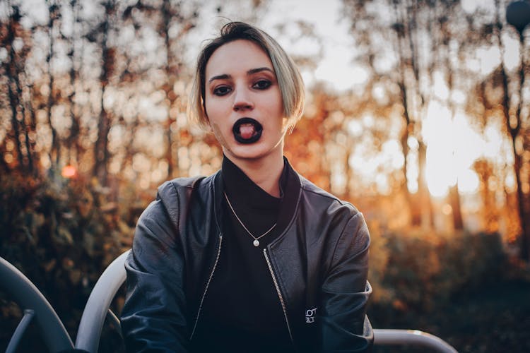 A Woman Wearing A Black Lipstick Sticking Her Tongue Out