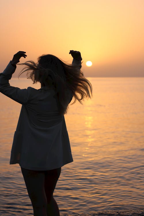 Free A Woman Standing on Seashore during Sunset Stock Photo
