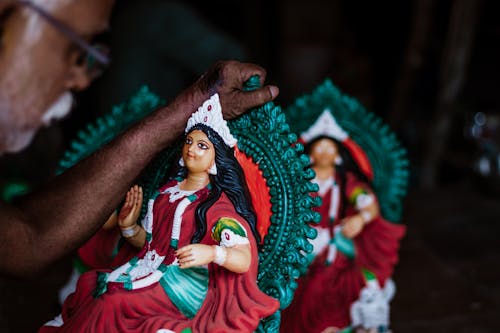Person Holding Green and Red Figurine