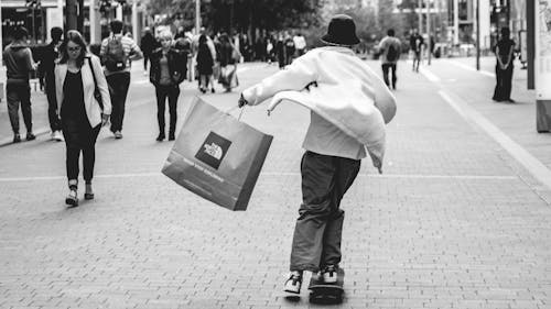 Free A Person Holding a Shopping bag while Skateboarding Stock Photo