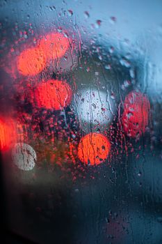 Raindrops streaming down a window with blurred city lights in the background create a moody ambiance.