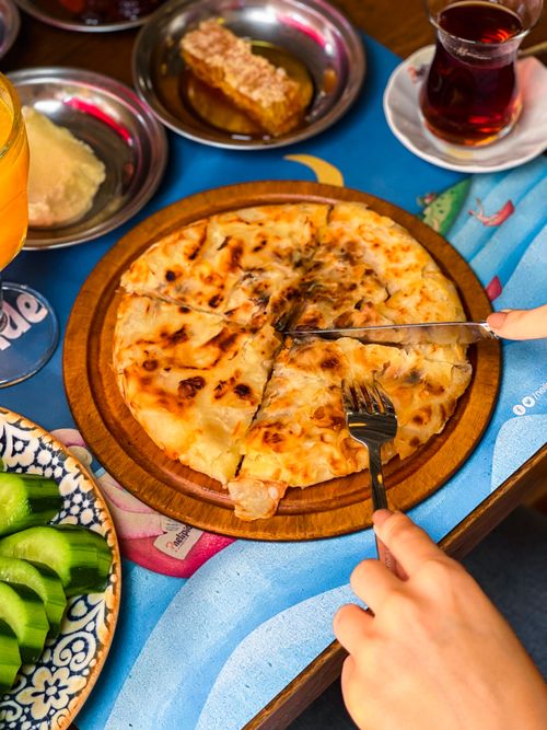 Free Freshly baked cheese pizza being sliced, surrounded by appetizers on a vibrant table setting. Stock Photo