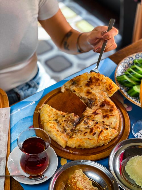 Free Savoring a slice of Turkish pide paired with aromatic tea in a warm indoor atmosphere. Stock Photo
